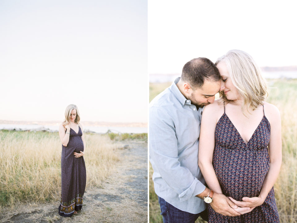 A young pregnant couple stand in a golden field on vashon island