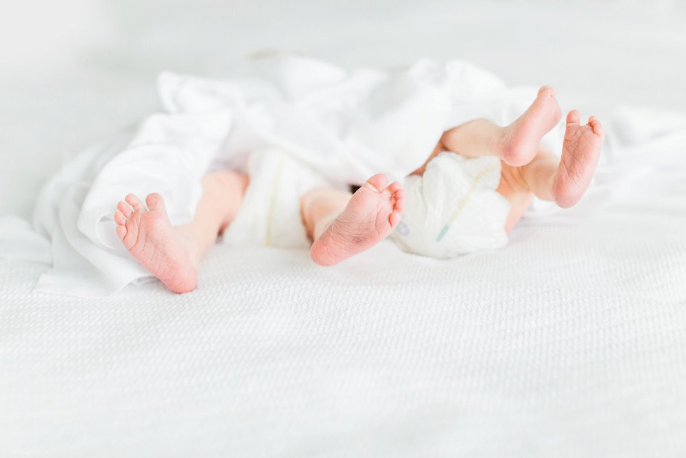 A detail photo of the twin babies toes surrounded by a white blanket