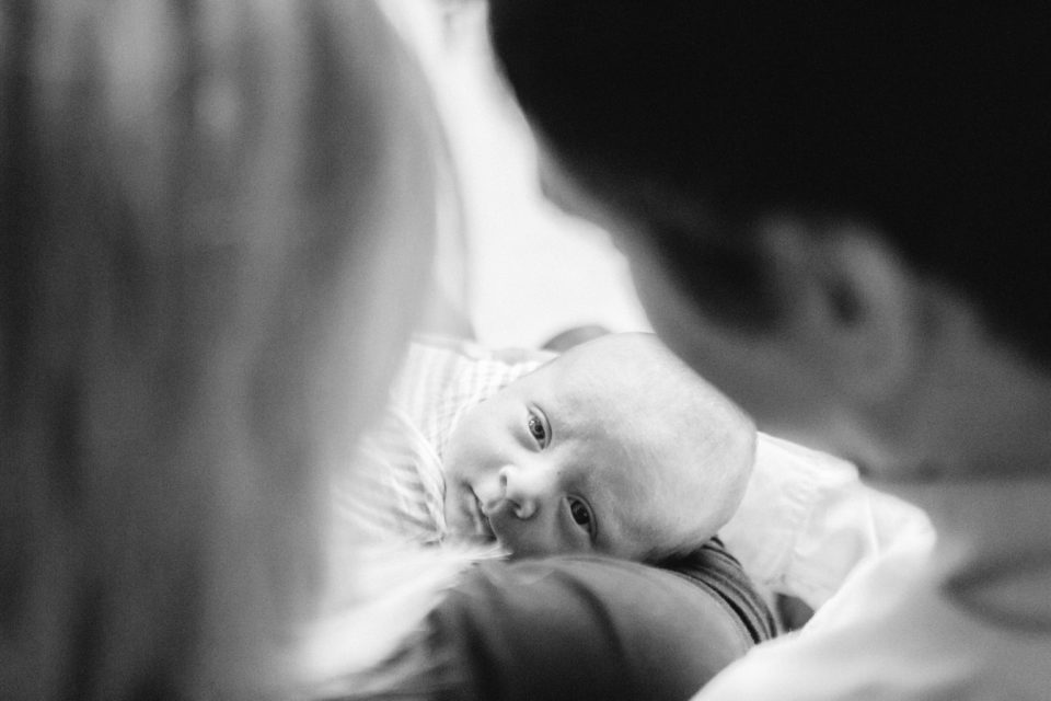  Newborn baby stairs up between parents heads at photographer 