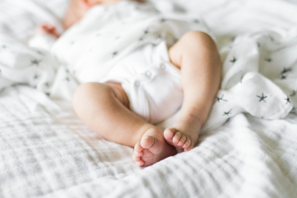  Dreamy photo of a babies toes as he lays on a white blanket 