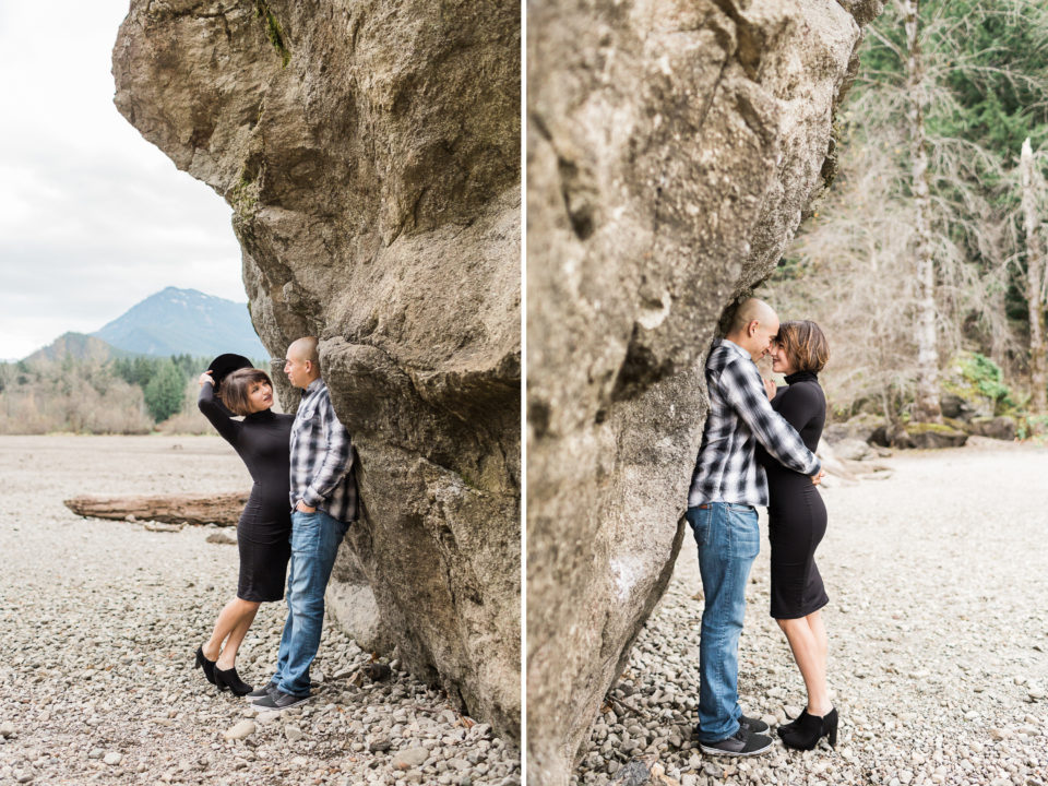 A sweet couple holds each other as they lean against a large rock