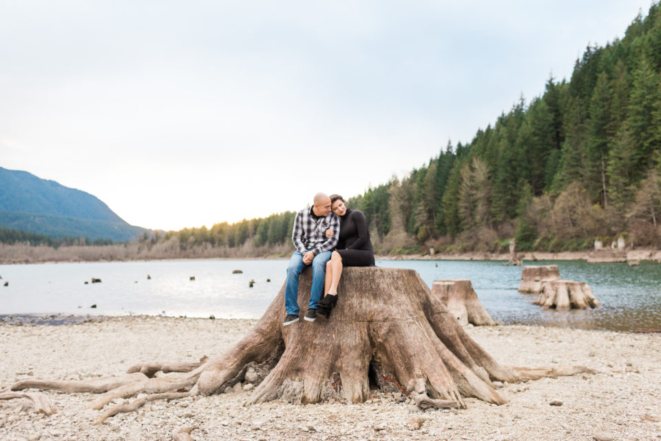 A couple cuddles on a tree stump during their Rattlesnake Lake Couples Session