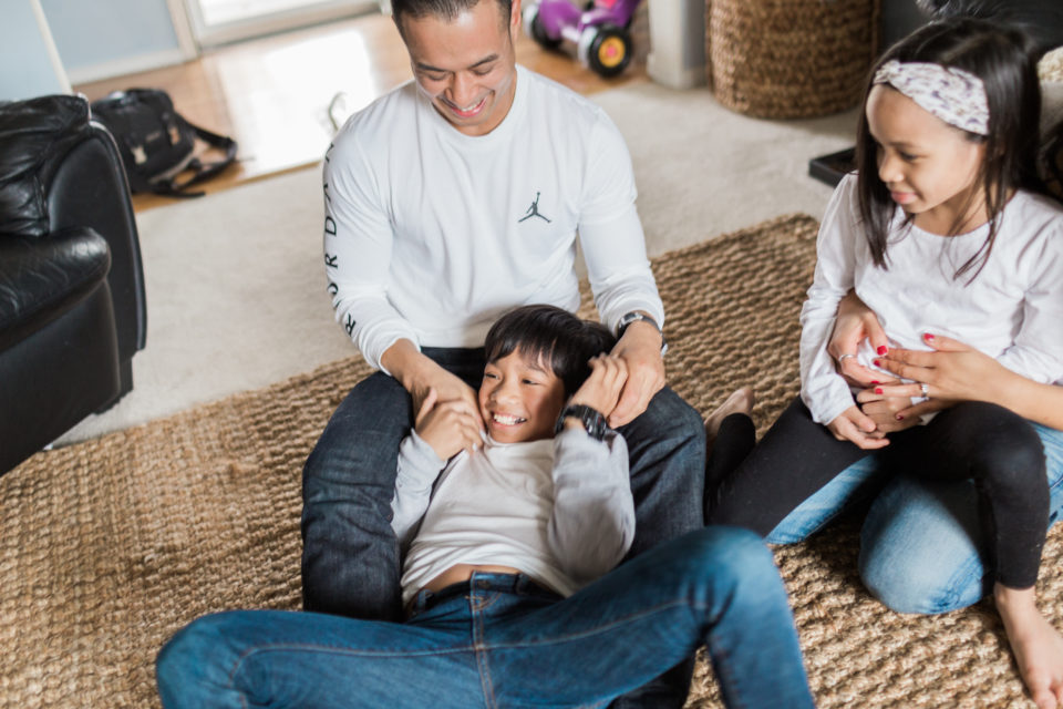 A young family has a fun time playing on the living room floor during their lifestyle family photo session