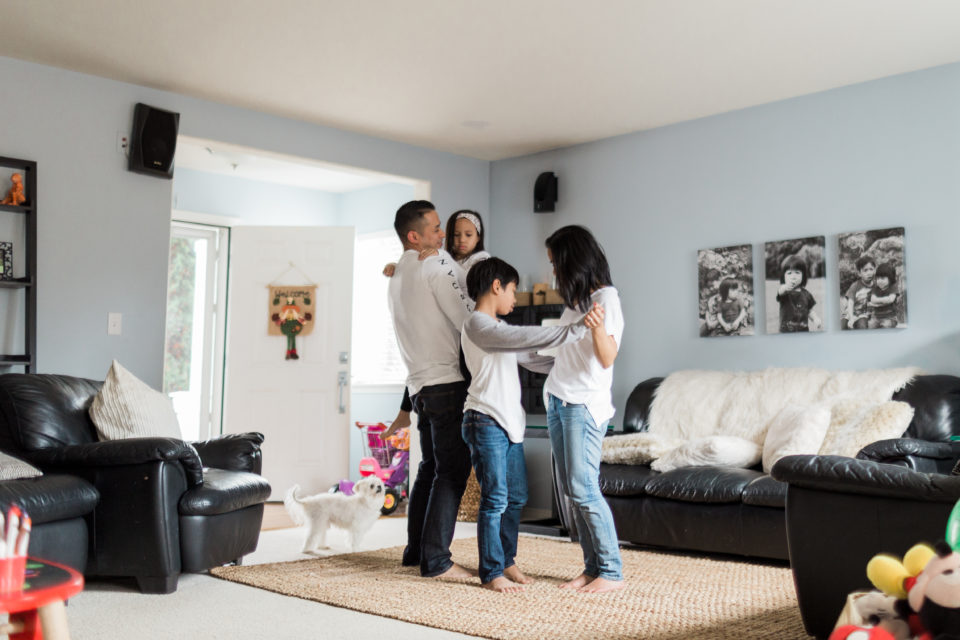 A family of four dances together in their home