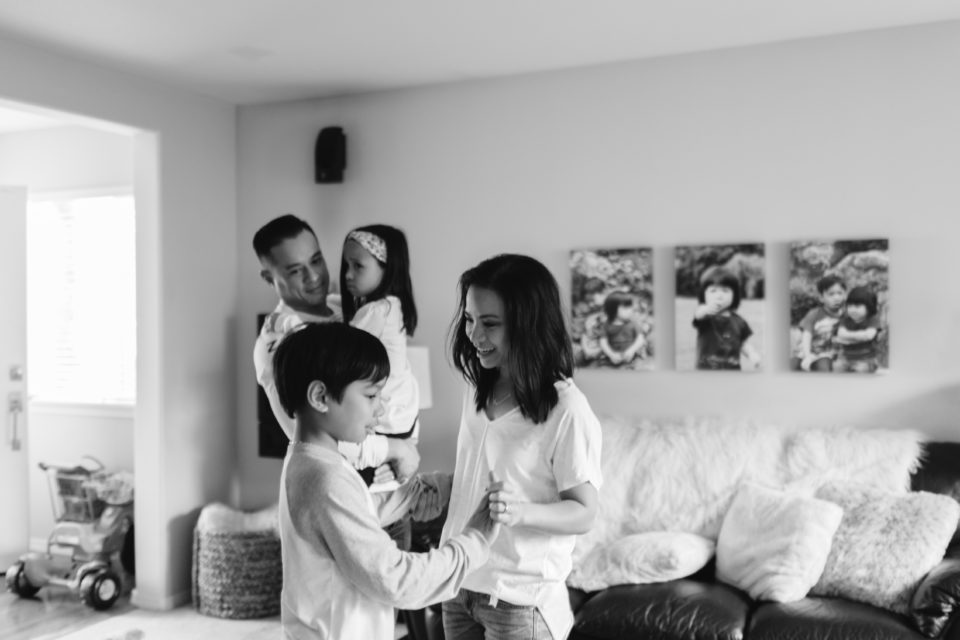 A dad watches his wife and son have a sweet moment as they dance together