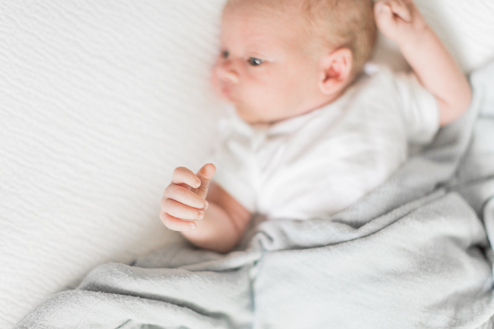Tiny newborn fingers in focus over his smiling face