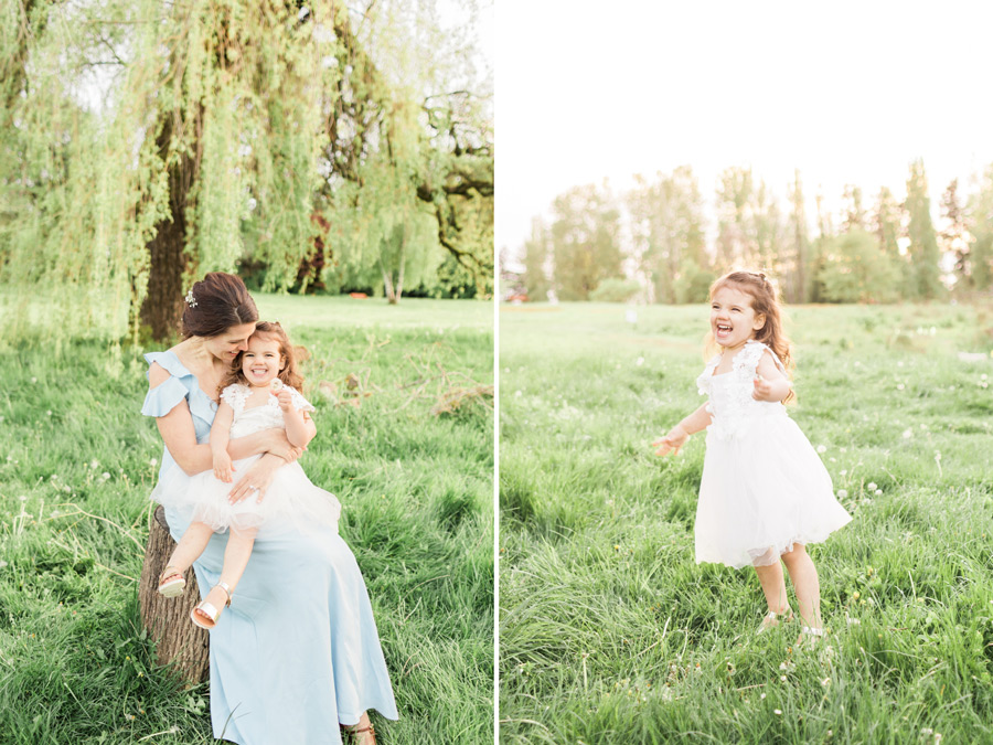 A toddler girl dances and smiles with glee in a pretty white dress