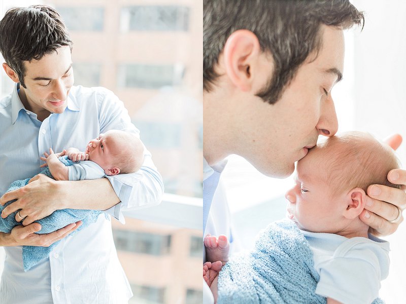 A newborn baby boy is kissed by his father tenderly on his forehead