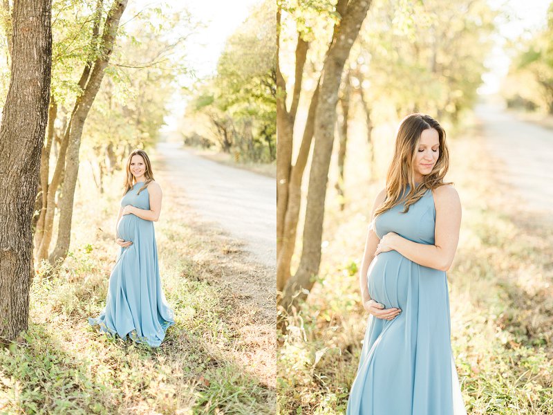 A pregnant woman wearing a long blue dress holds her growing bump and smiles
