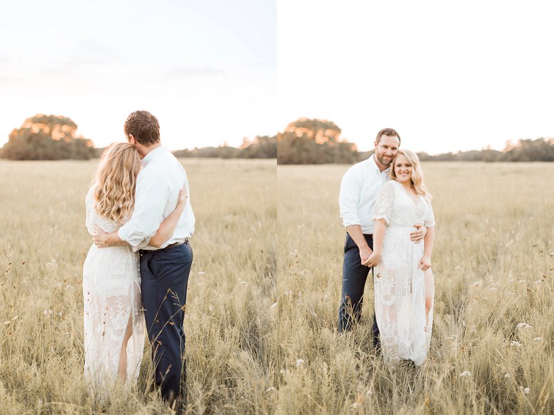 A couple holds each other with their arms around their waists as they look into the sunset