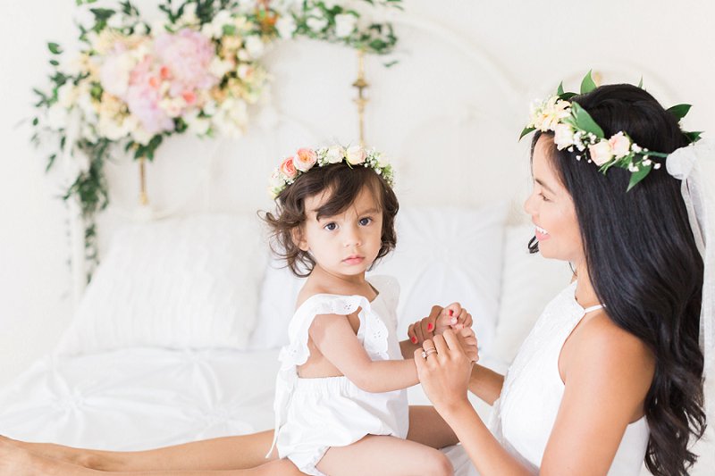 The young Mother admires her sweet daughters round face framed by a gorgeous flower crown