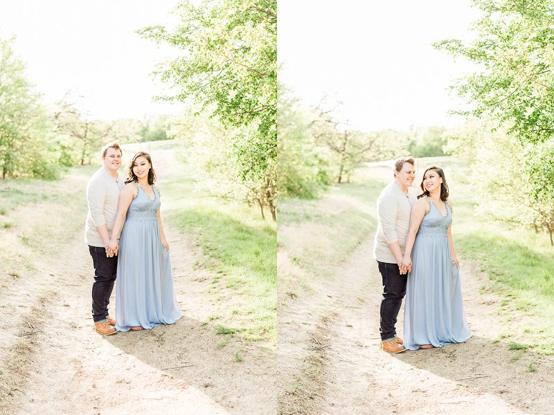 As they stand in the middle of a dirt path the married couple hold hands and smile