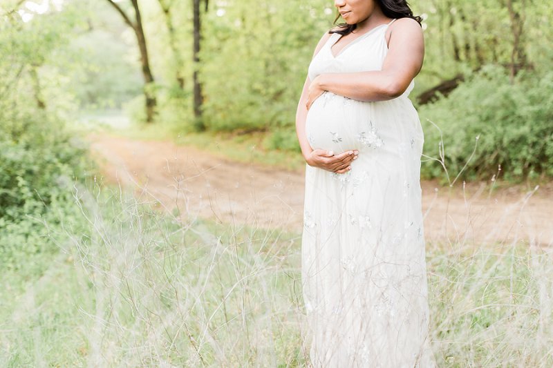 The growing belly of a pregnant woman is the focus of this photo with gorgeous light shining in the background