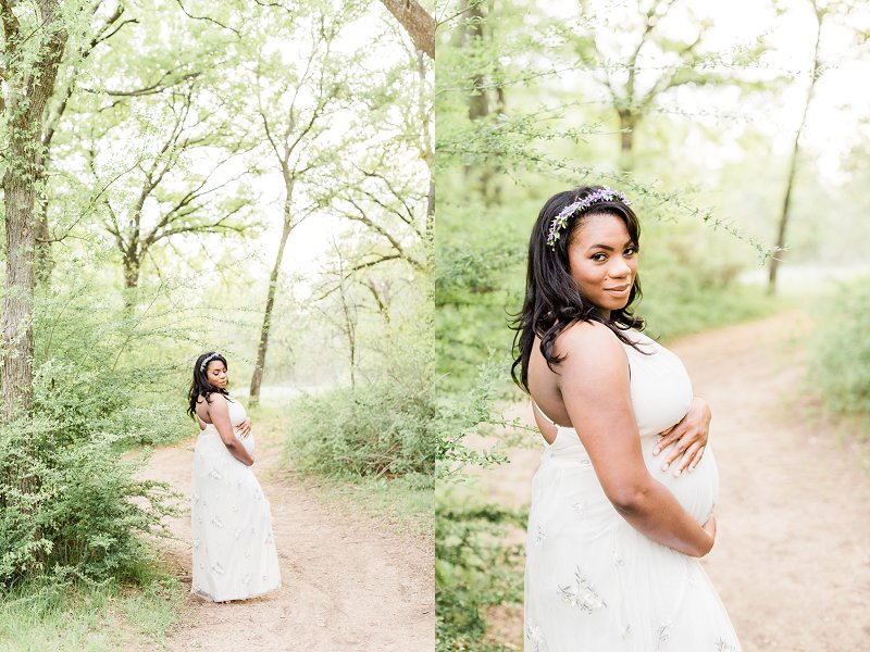 A pregnant woman is surrounded by trees as she poses in her cream floral dress