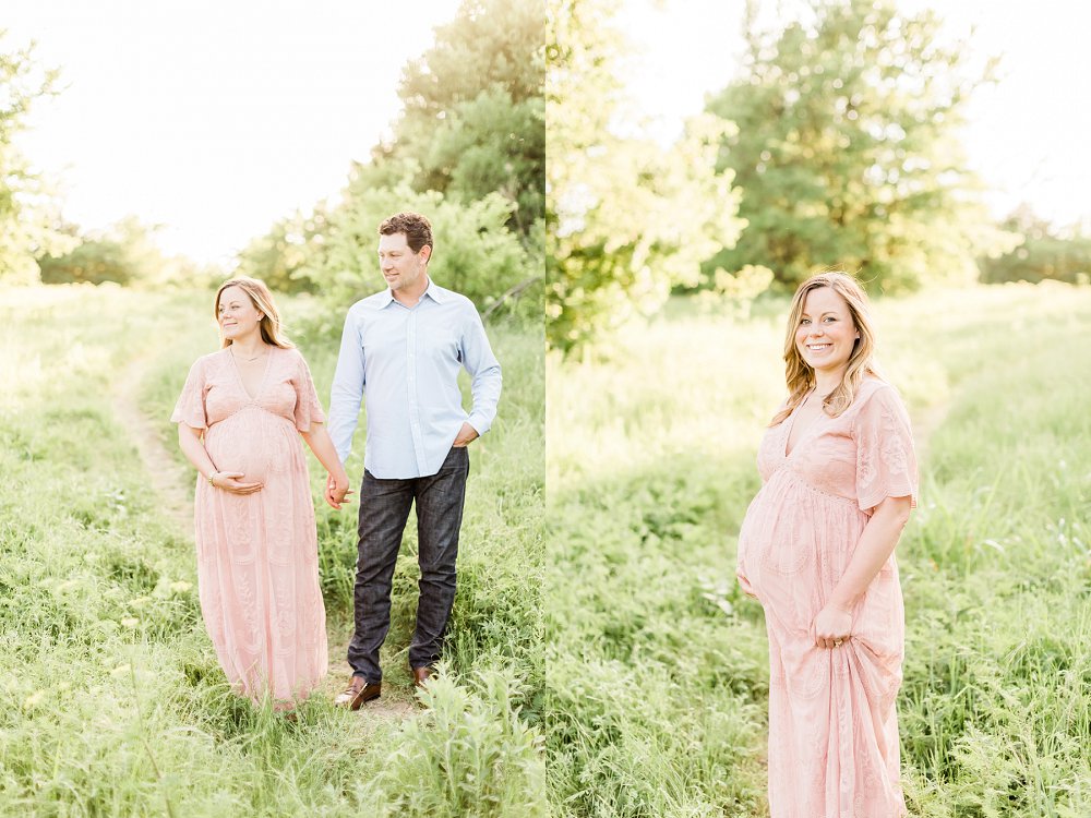 A woman with a growing baby bump clutches the fabric of her pink lace dress and smiles at the camera