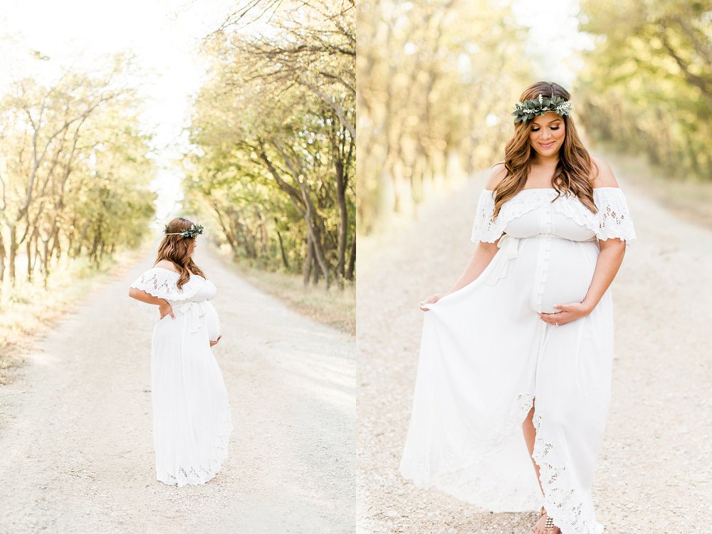 The pregnant woman walks down the tree lined path and holds her white fillyboo dress