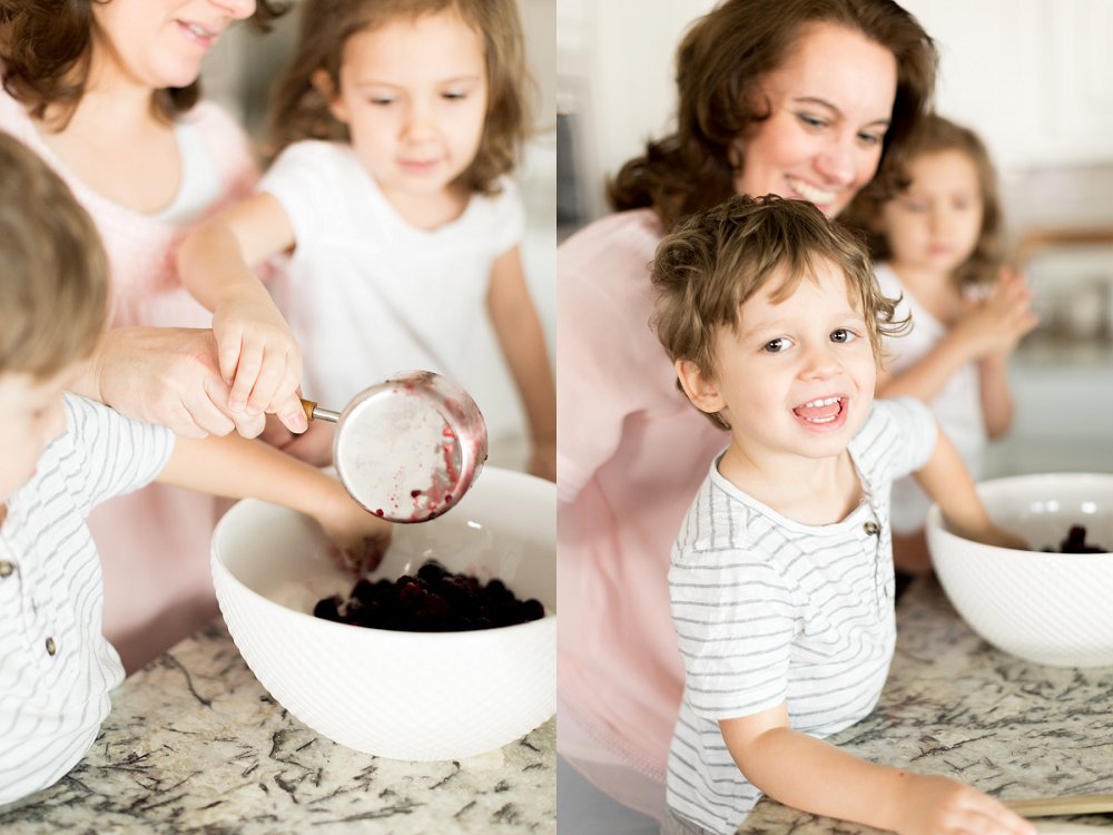 The little boy flashes a wide grin at the camera as he sneakily grabs a berry out of the mixing bowl