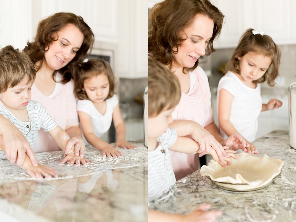 Two children are helping their Grandmother make pie crust in a white kitchen