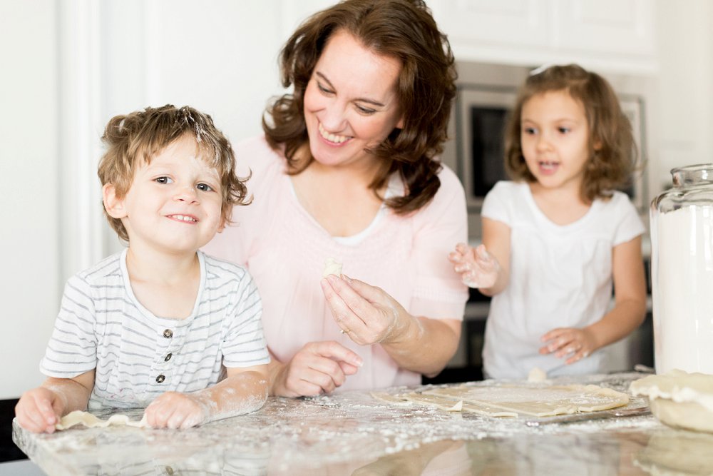 The two laugh together as they notice the little boy is covered in flour