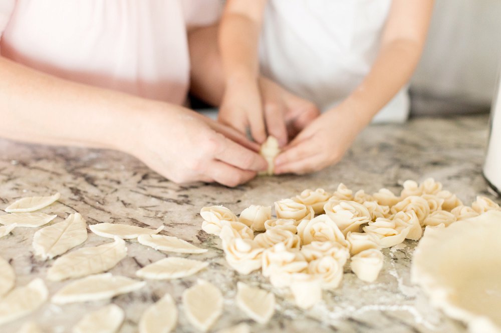 A detail photo of the little girl and her Mother's hands working together to make leaves out of the pie crust