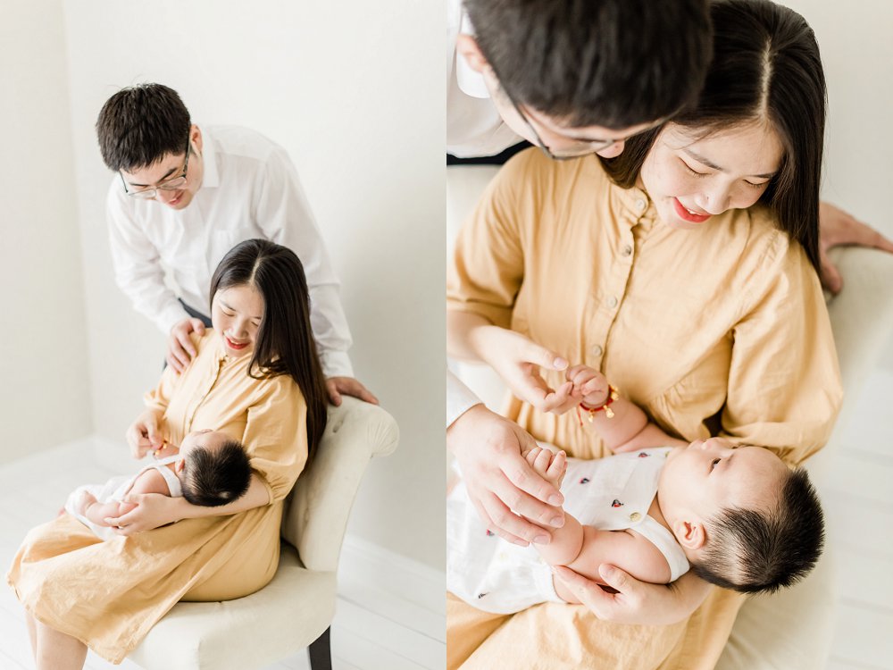A mother holds her baby while her husband admires the baby over her shoulder