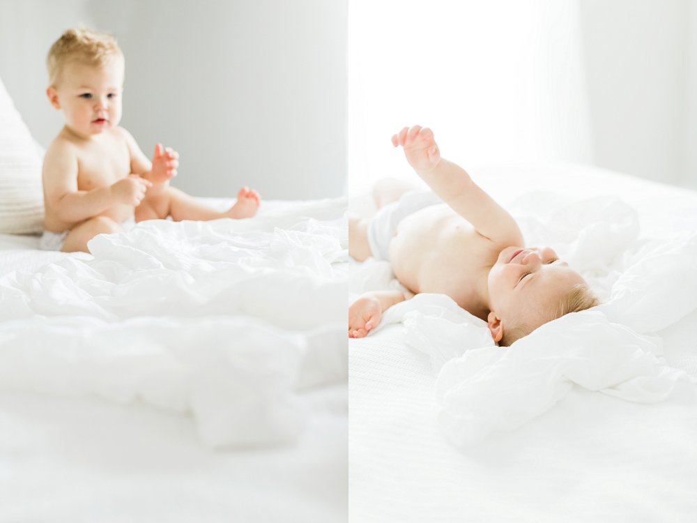 The baby playfully rolls around the bed with a smile on his face