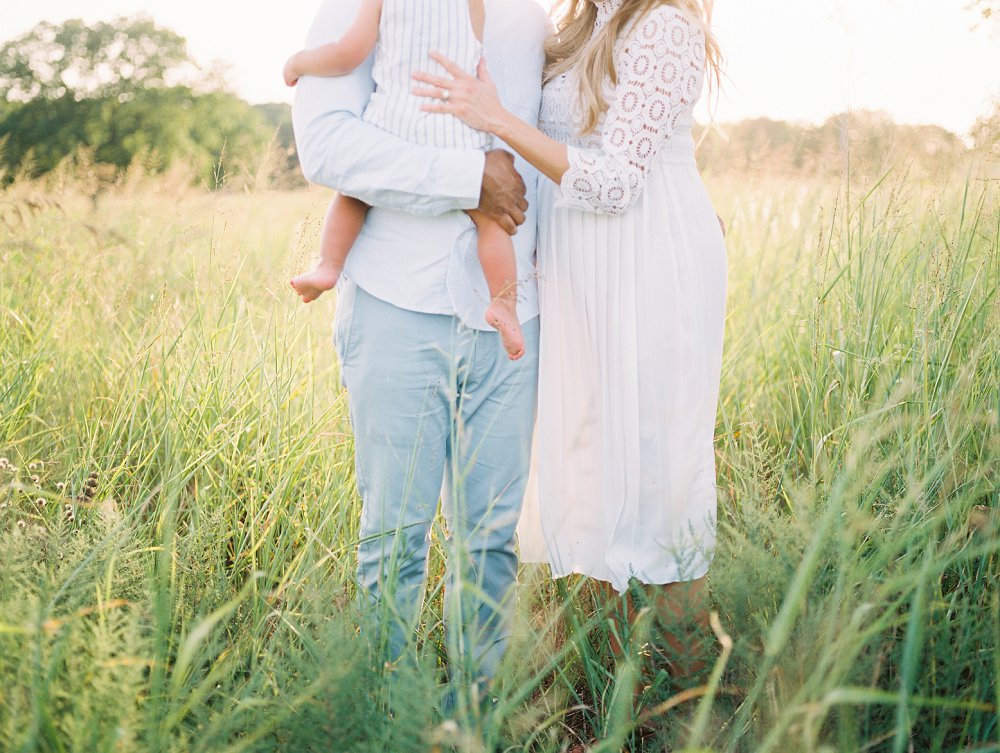 The tall grass surrounds the family's legs as they wrap their arms around each other
