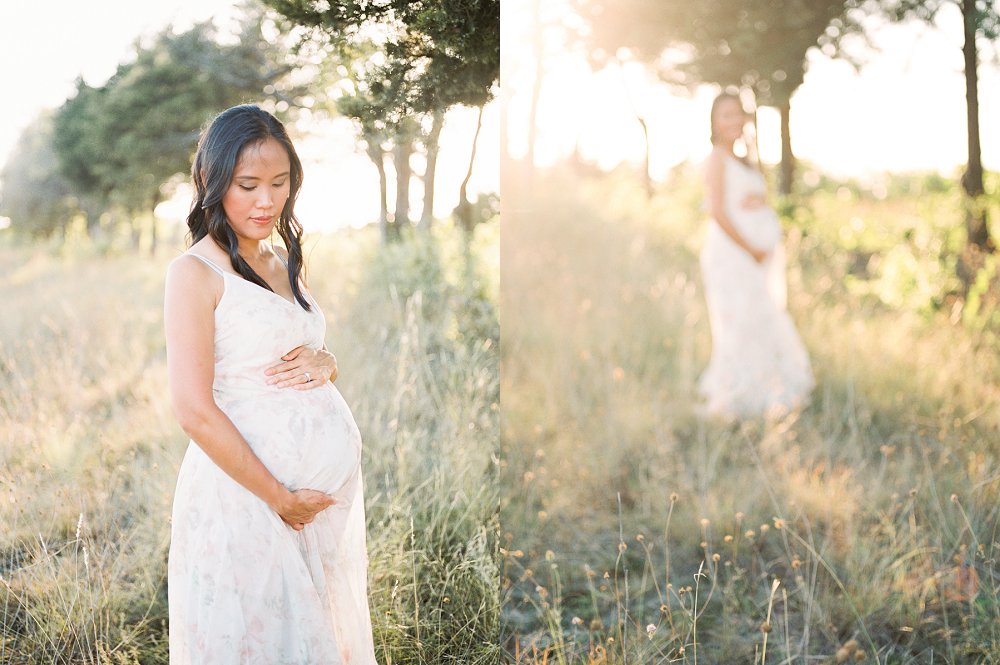 A mother with dark hair wearing a pink floral chiffon dress smiles at her baby bump