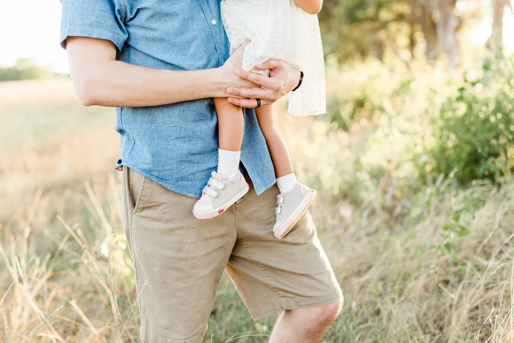 A detail photo of Dad's arms wrapped around his little girl
