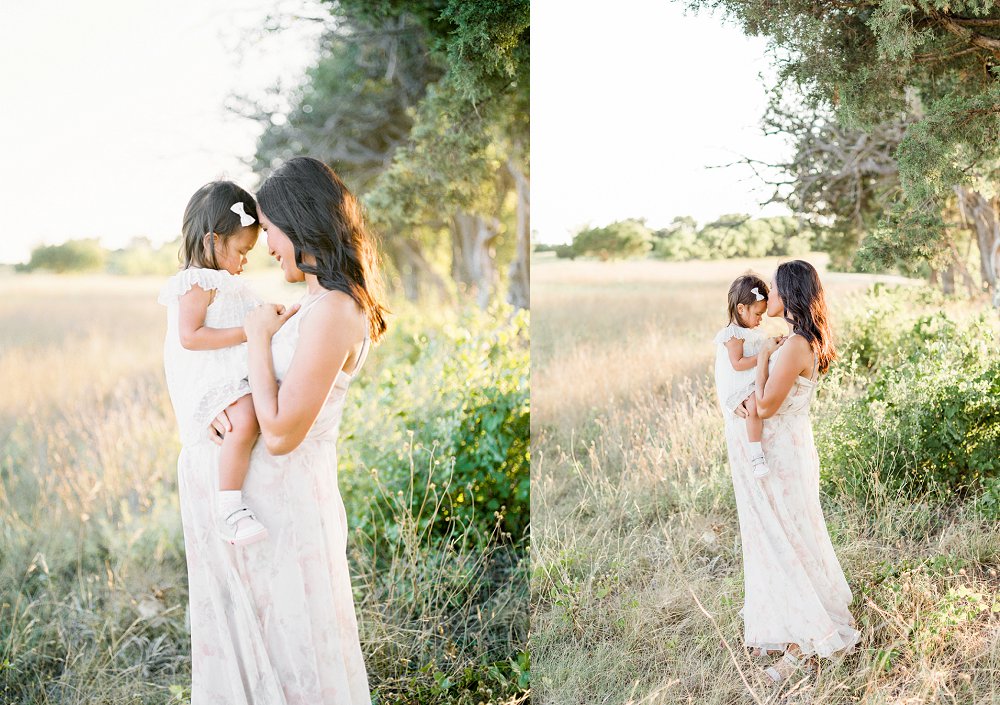 The young mother leans in and gives her young daughter a kiss on the forehead