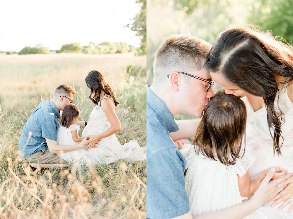 Mom and Dad lean in and kiss their daughter on the head together