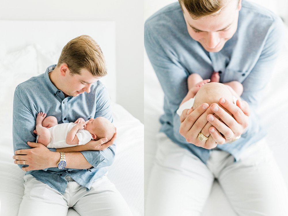 Dad smiling and staring lovingly at newborn baby girl as he cradles her in his arms