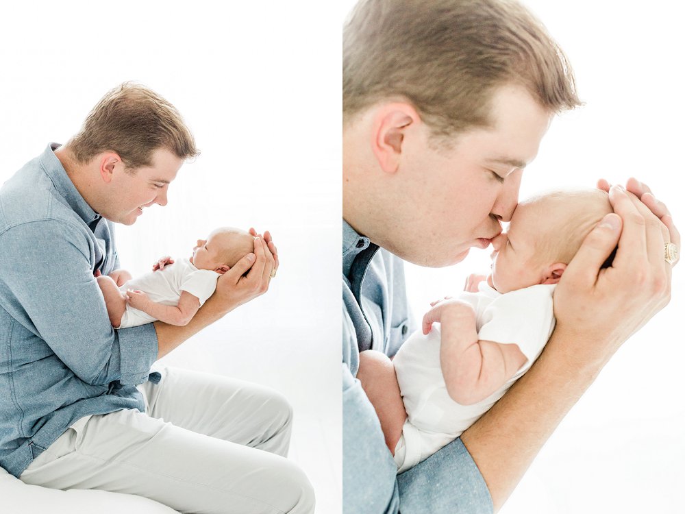 Dad smiling at and kissing newborn baby girl in light and bright newborn photos