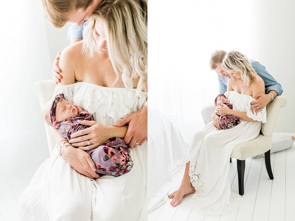 Mom and Dad hold newborn baby in light and bright photo studio