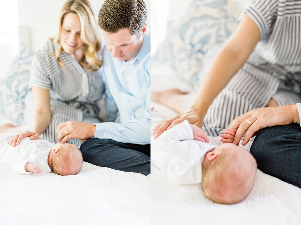 Dad and Mom smile at baby boy and hold his tiny fingers