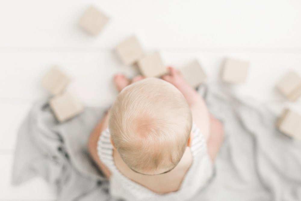 A photo from above as baby boy plays with wooden blocks