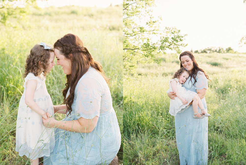 A little girl is happily snuggled into her mothers arms as the sun sets behind them